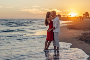 The goal of all calgary sex therapists: Sunset photo of a couple standing on the edge of a beach in the waves kissing in a passionate embrace